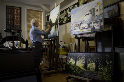 Canadian painter Peer Christensen adds the finishing touches to a large canvas in his studio overlooking George Street. Three large paintings sit on or against easels in this carefully lit scene by photographer Mike Taylor.